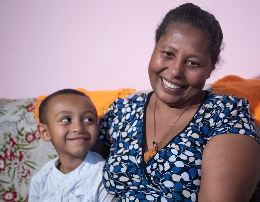 Smiling son looking at smiling mother while they are sat on a couch