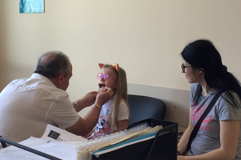 Mother watching her daughter undergo a physical exam from a surgeon