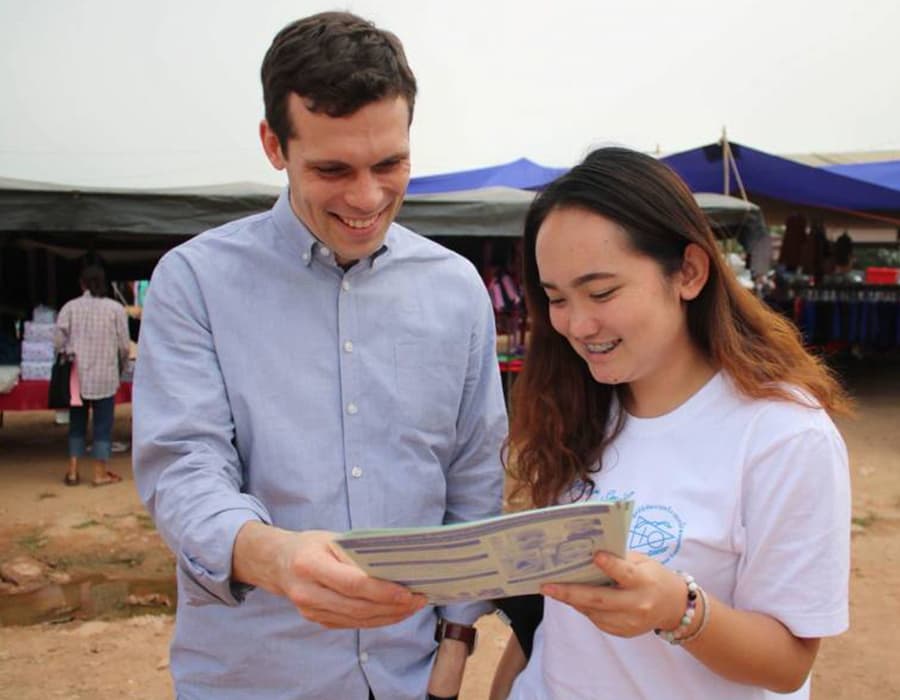 Hugh Brewster and a volunteer both smile as they look at a report together